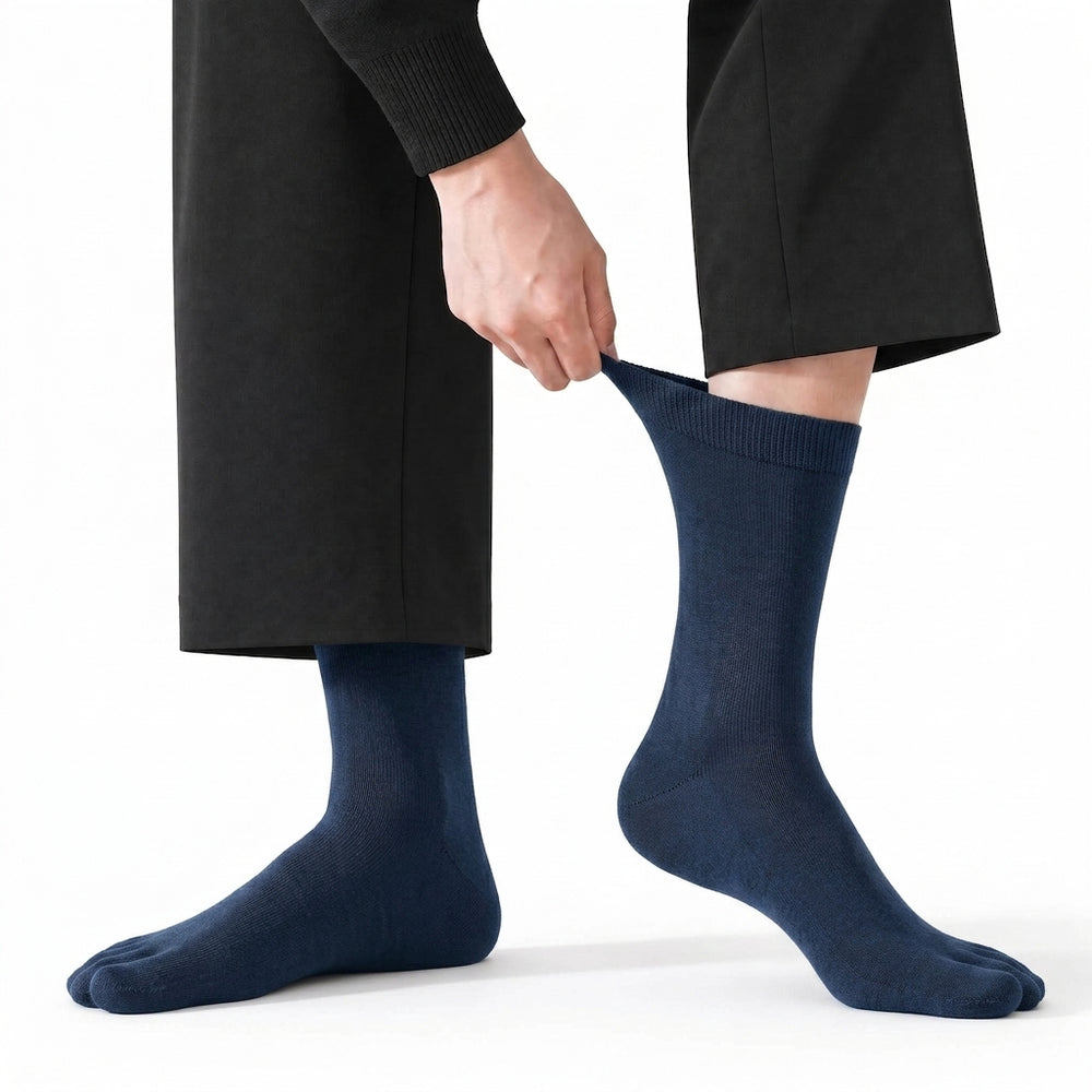 A hand drawing up the ribbed Lycra cuff of a ROMATOKI five-toe sock in Midnight, worn under a dark trouser hem