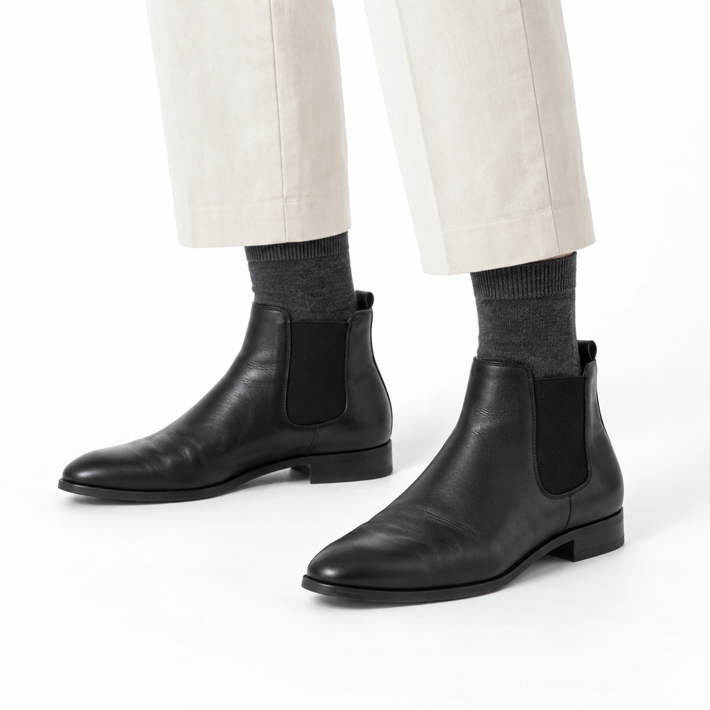 Charcoal socks above black ankle boots, with cream trousers against a white background.